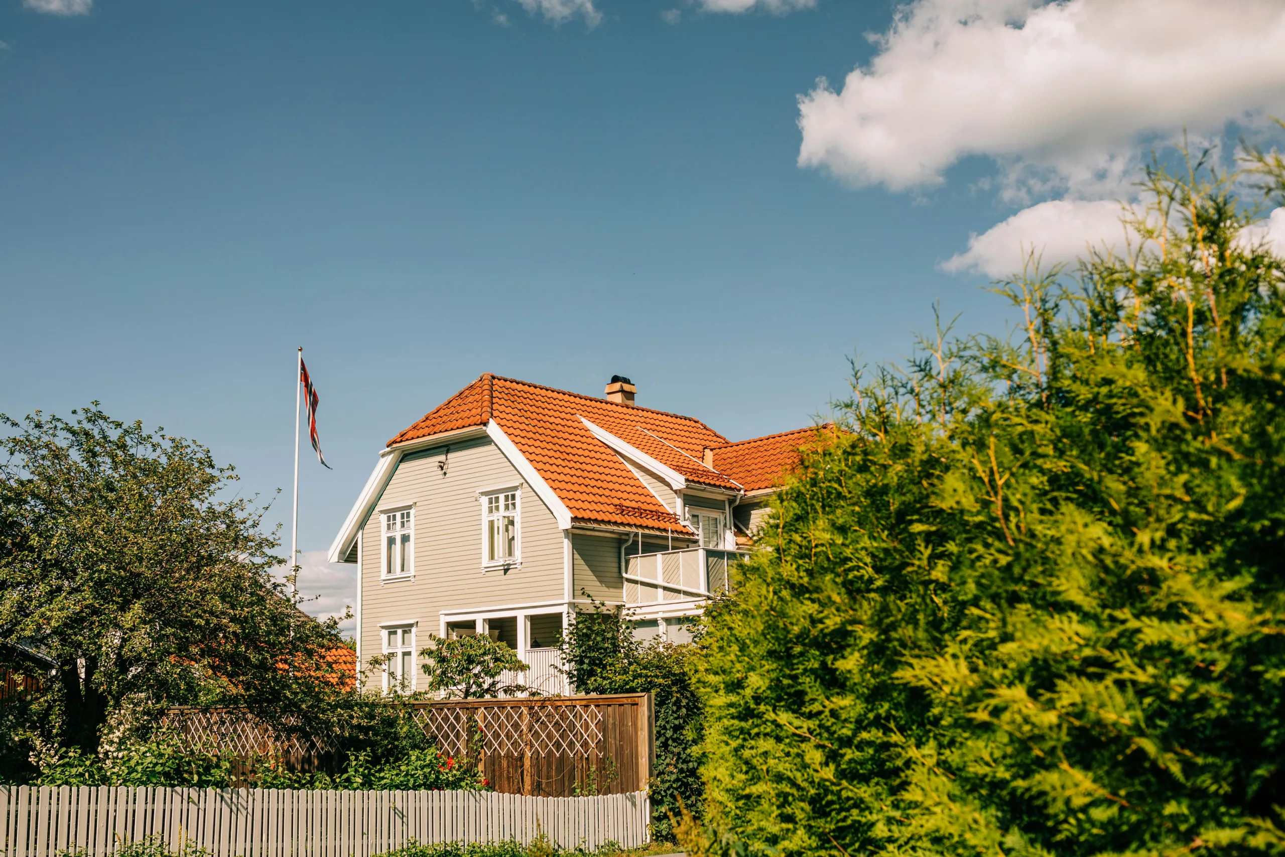 Villa med rött tak i grönskande trädgård.