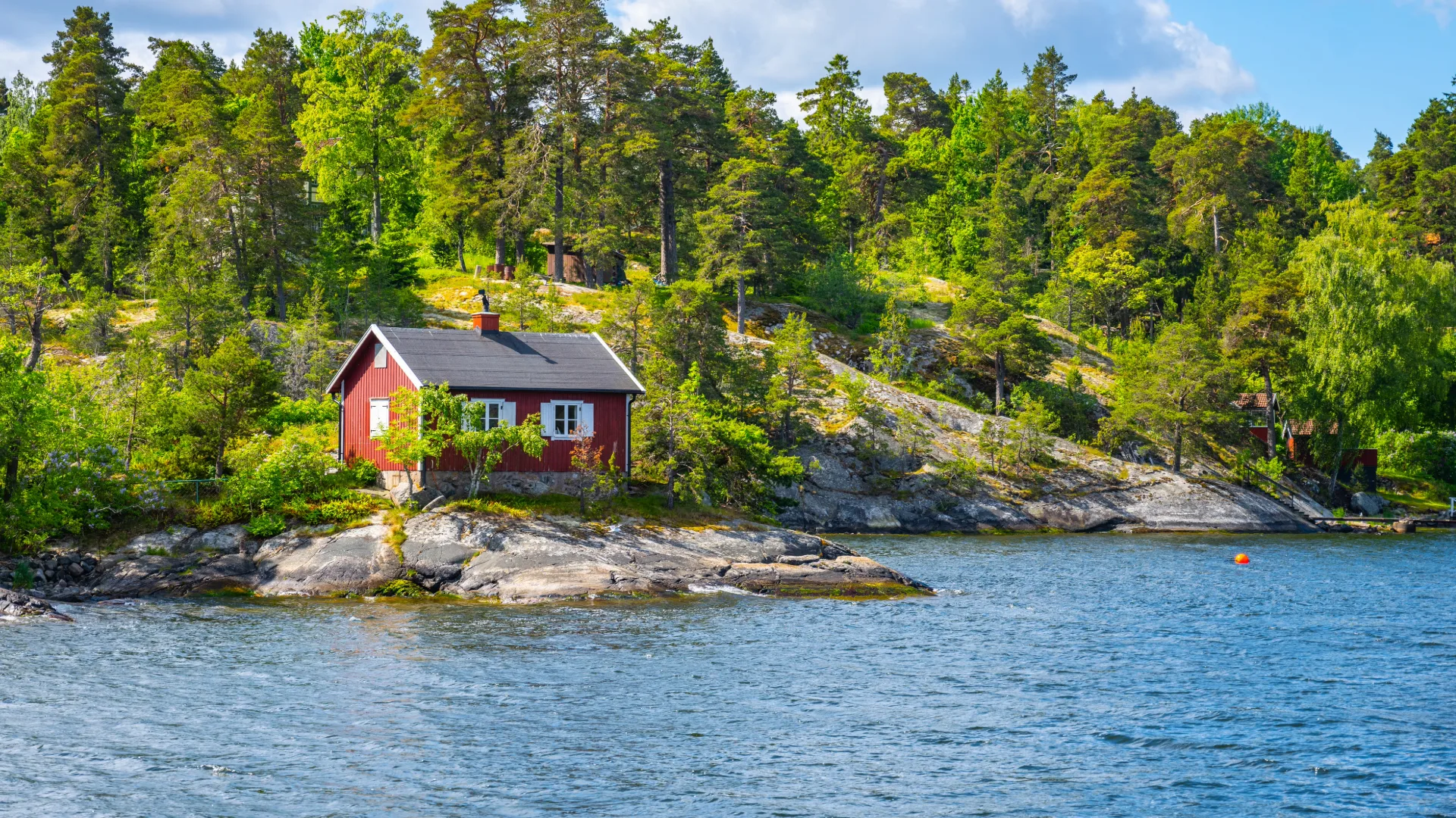 Vi ser en sommarstuga vid vattnet 